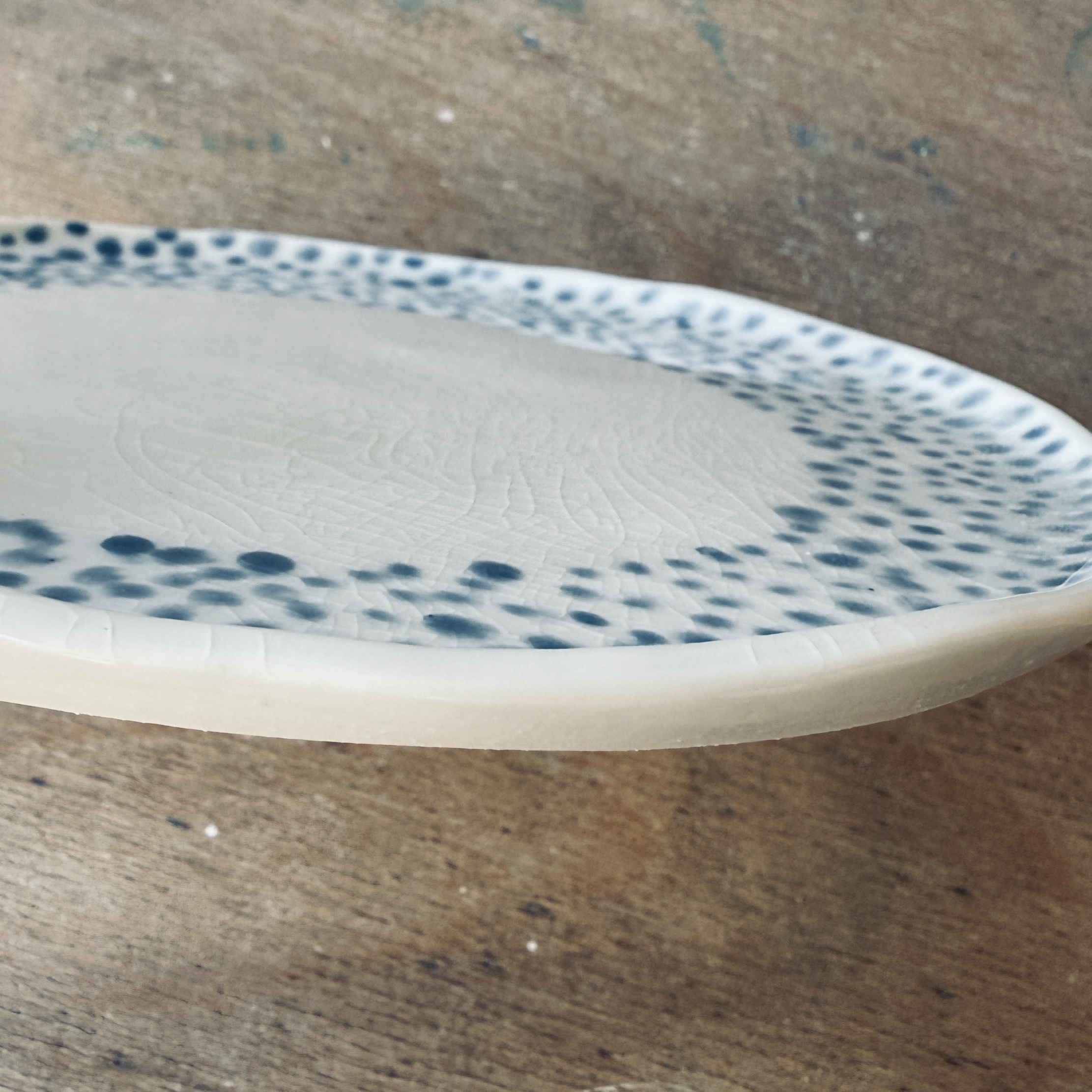 Assiette à dessert en porcelaine de la céramiste Martha Stahlkopf, motif couronne de points en bleu clair, vue de côté réalisée à Strasbourg