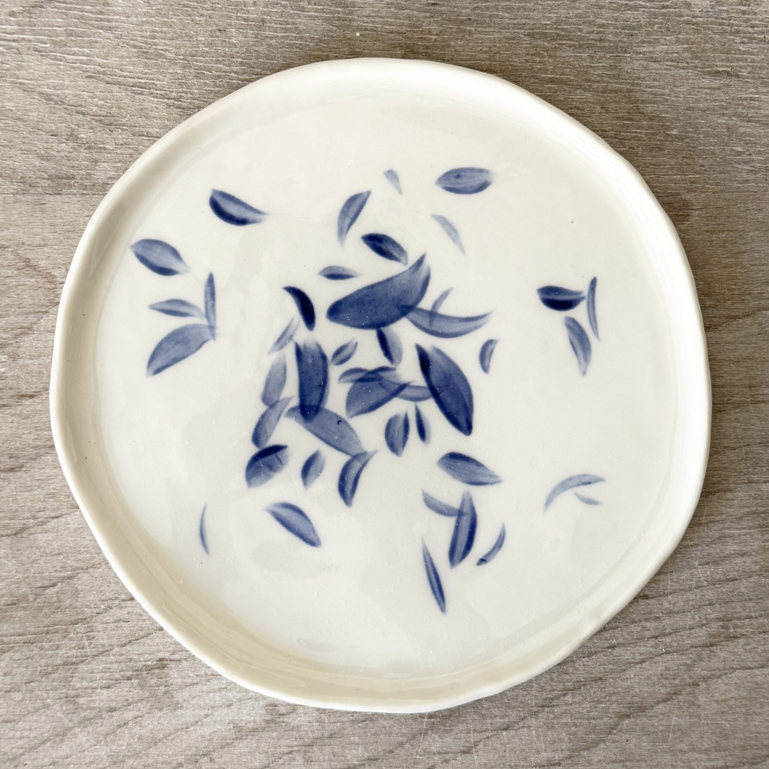 Assiette à dessert en porcelaine de la céramiste Martha Stahlkopf, motif feuilles bleues qui volent, réalisée à Strasbourg