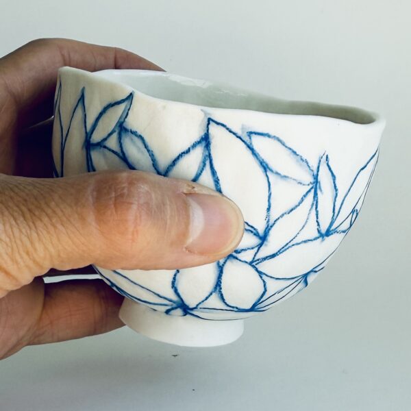 Petit bol en porcelaine motif contour de feuilles bleues, dessinées au crayon d'oxyde, en main, de Martha Stahlkopf