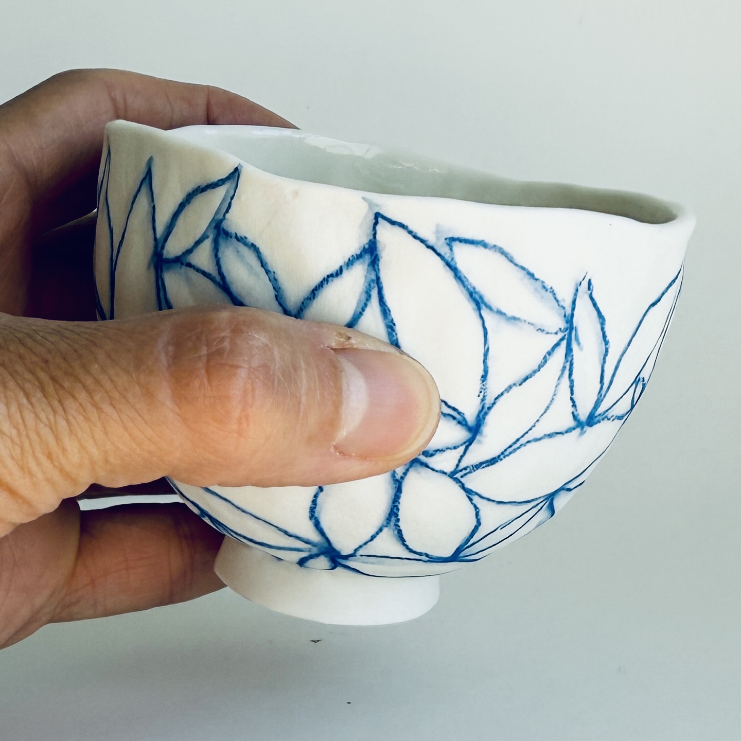 Petit bol en porcelaine motif contour de feuilles bleues, dessinées au crayon d'oxyde, en main, de Martha Stahlkopf