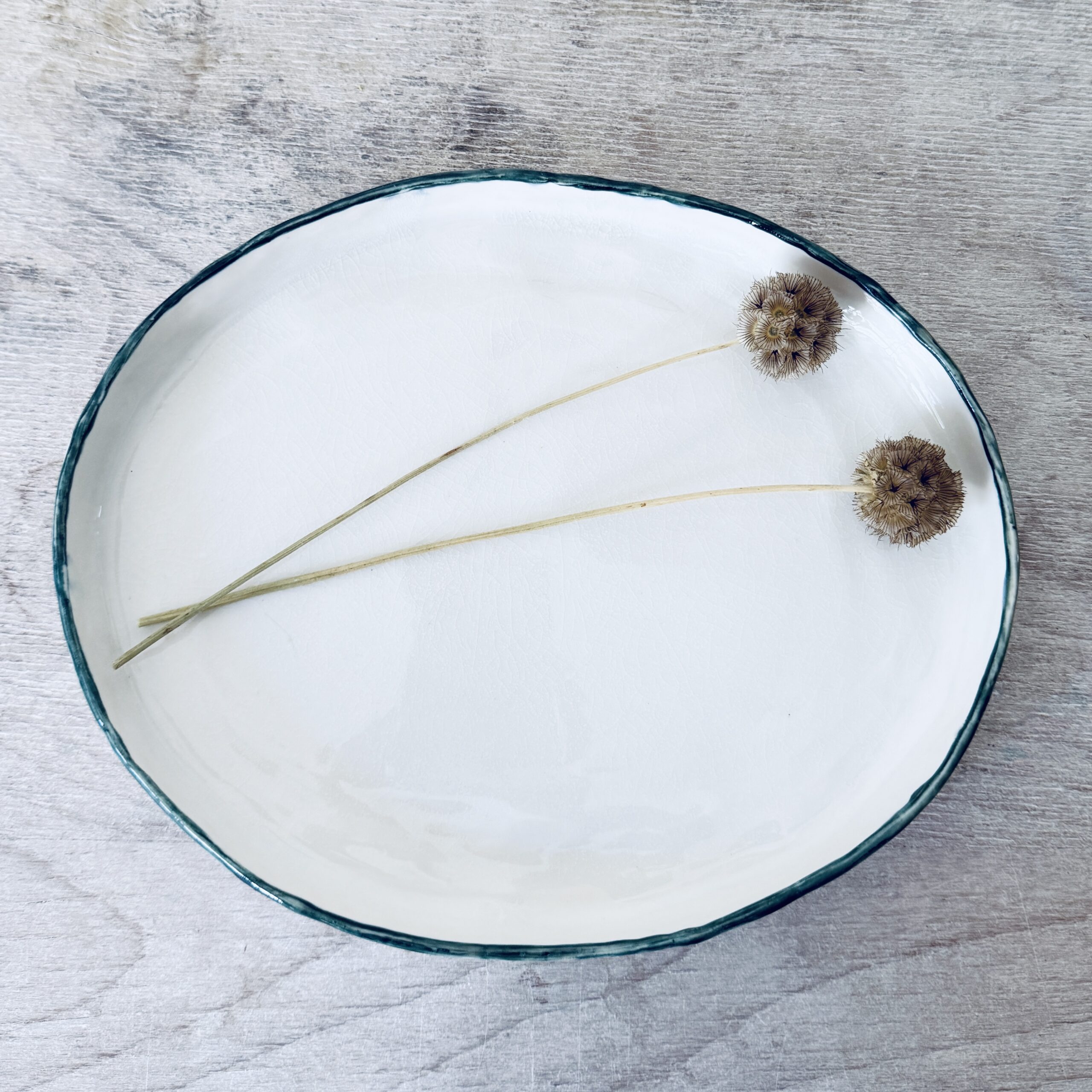 Plat en porcelaine avec petit rebord liseré vert pétrole et blanc façonné à la main par la céramiste Martha Stahlkopf dans son atelier à Strasbourg.