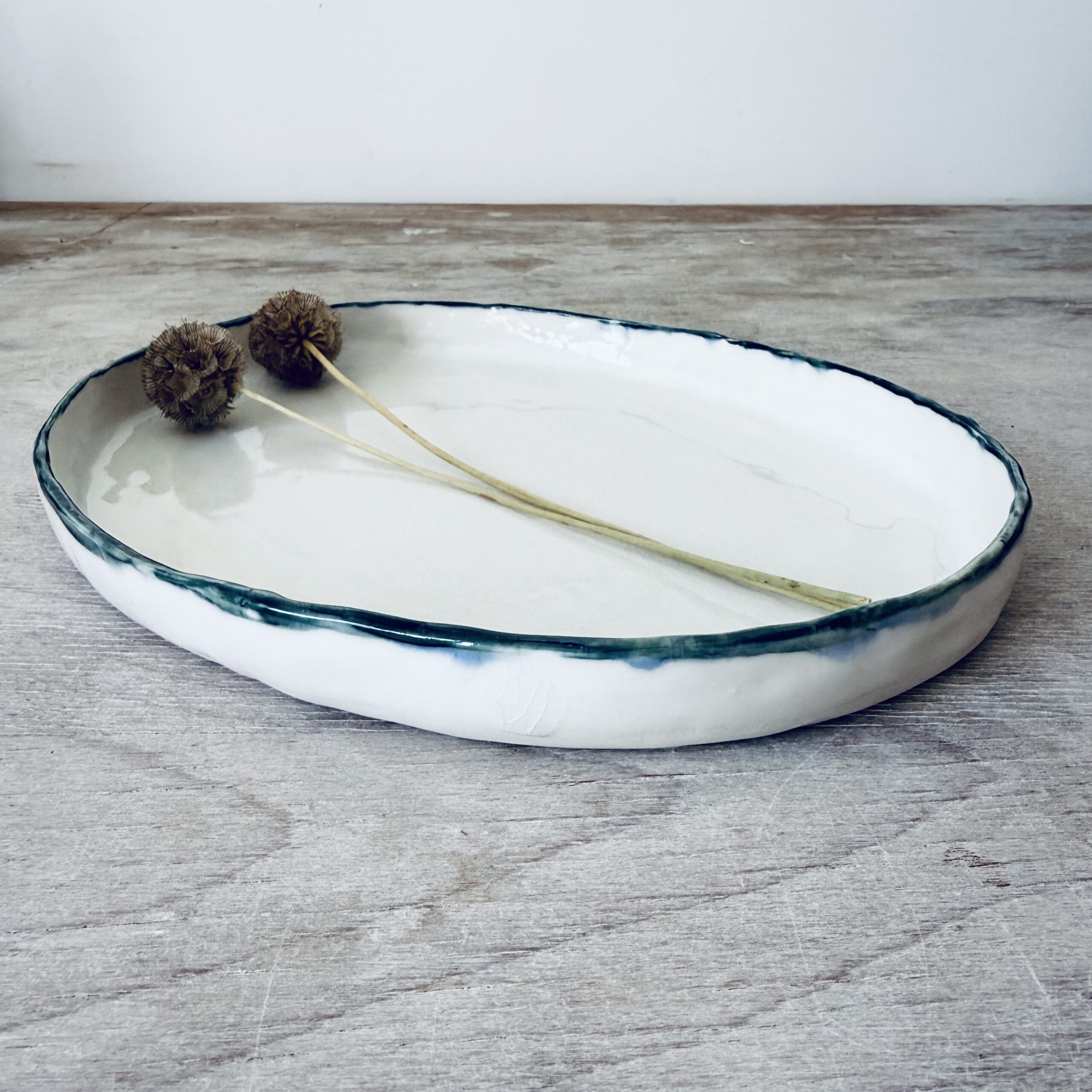 Plat en porcelaine avec petit rebord liseré vert pétrole et blanc façonné à la main par la céramiste Martha Stahlkopf dans son atelier à Strasbourg.