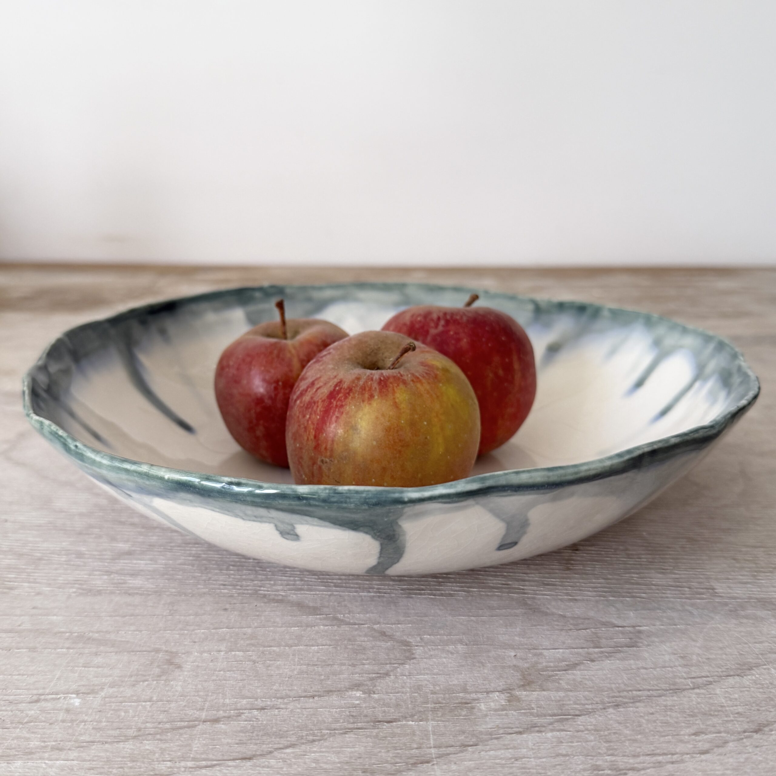 Saladier bas en porcelaine blanc avec liseret vert pétrole fait par la céramiste Martha Stahlkopf dans son atelier à Strasbourg.